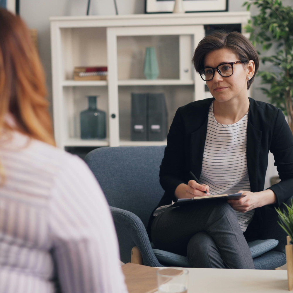Coach in gesprek met een cliënt in een lichte praktijkruimte