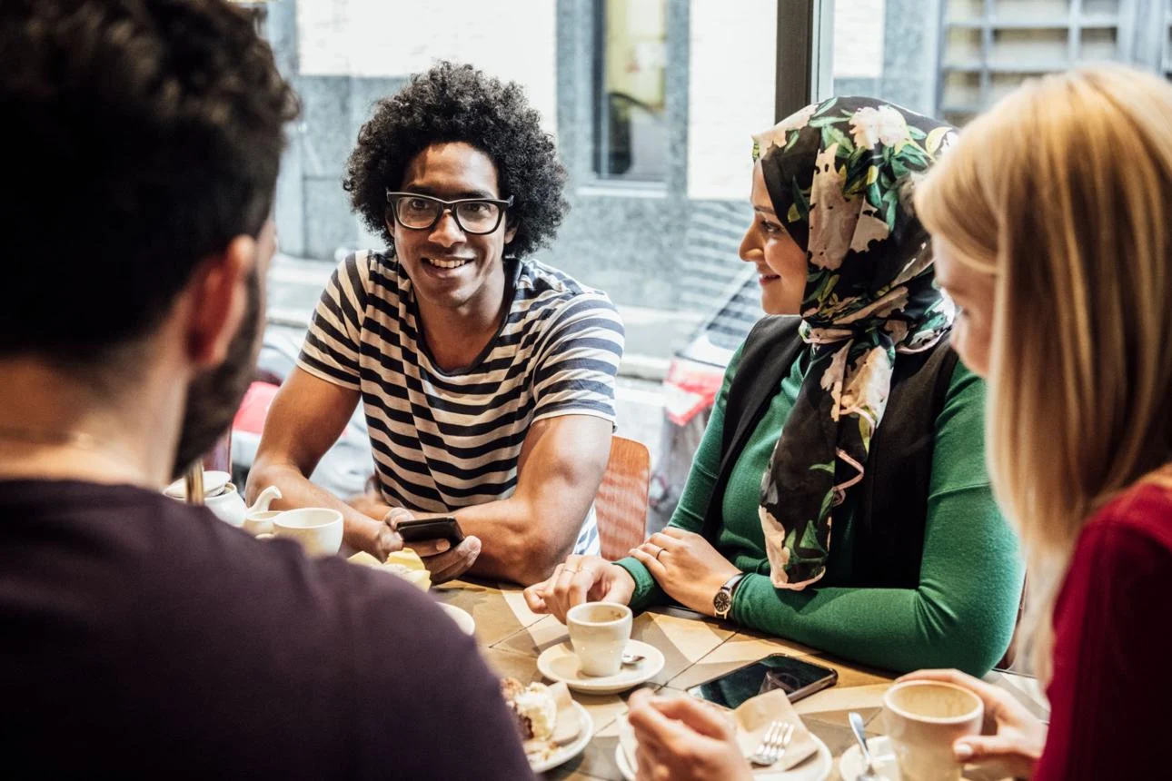 Mensen zitten rond een tafel in een gezellig lokaal café en praten met elkaar