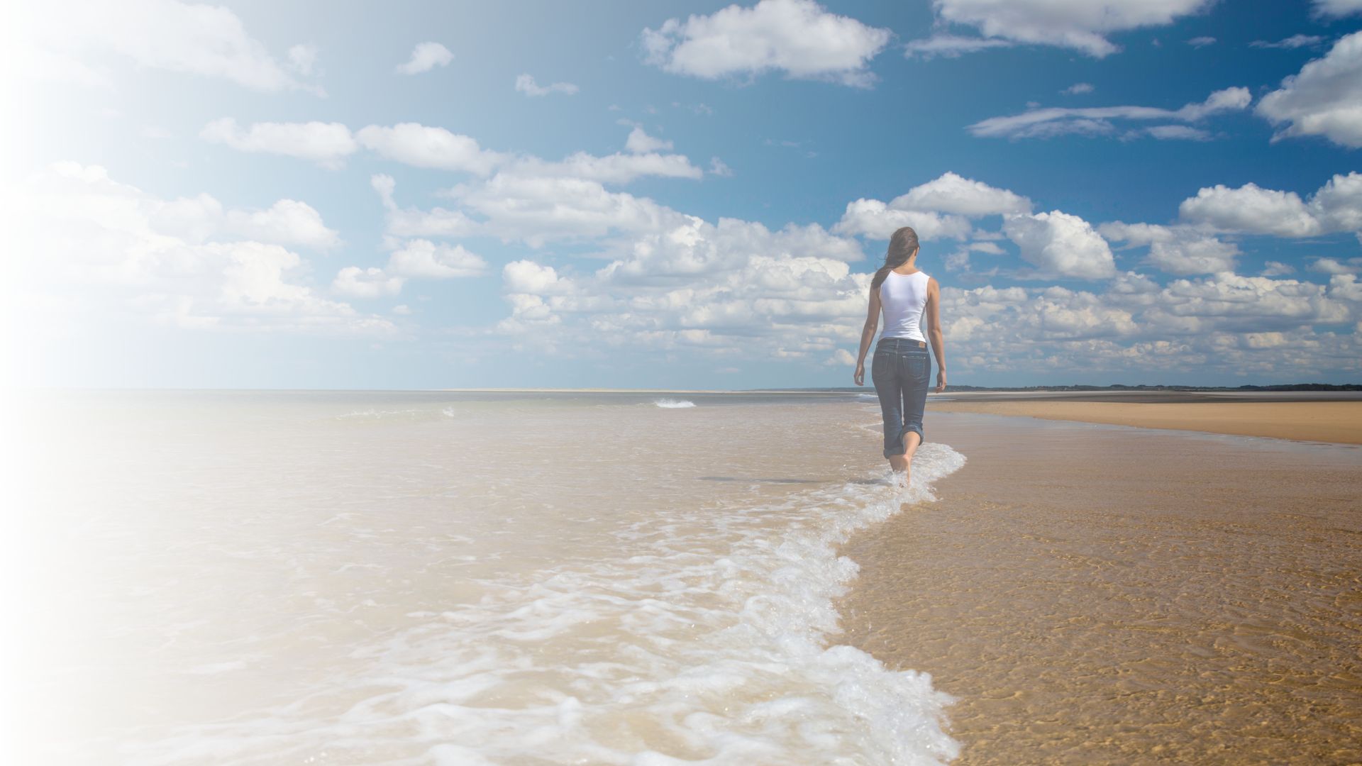 Vrouw wandelt over het strand langs de zee